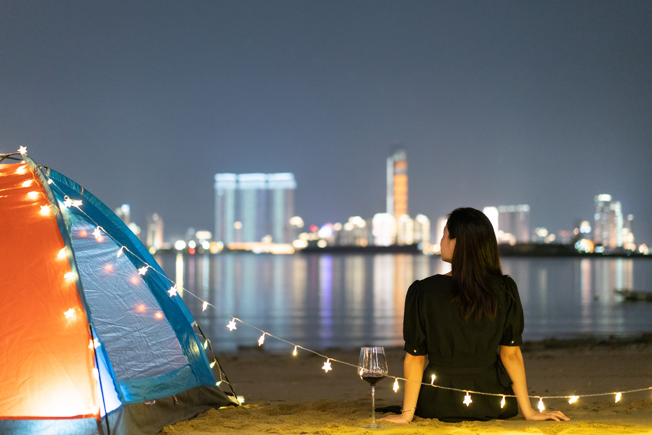 Girl camping by the sea at night